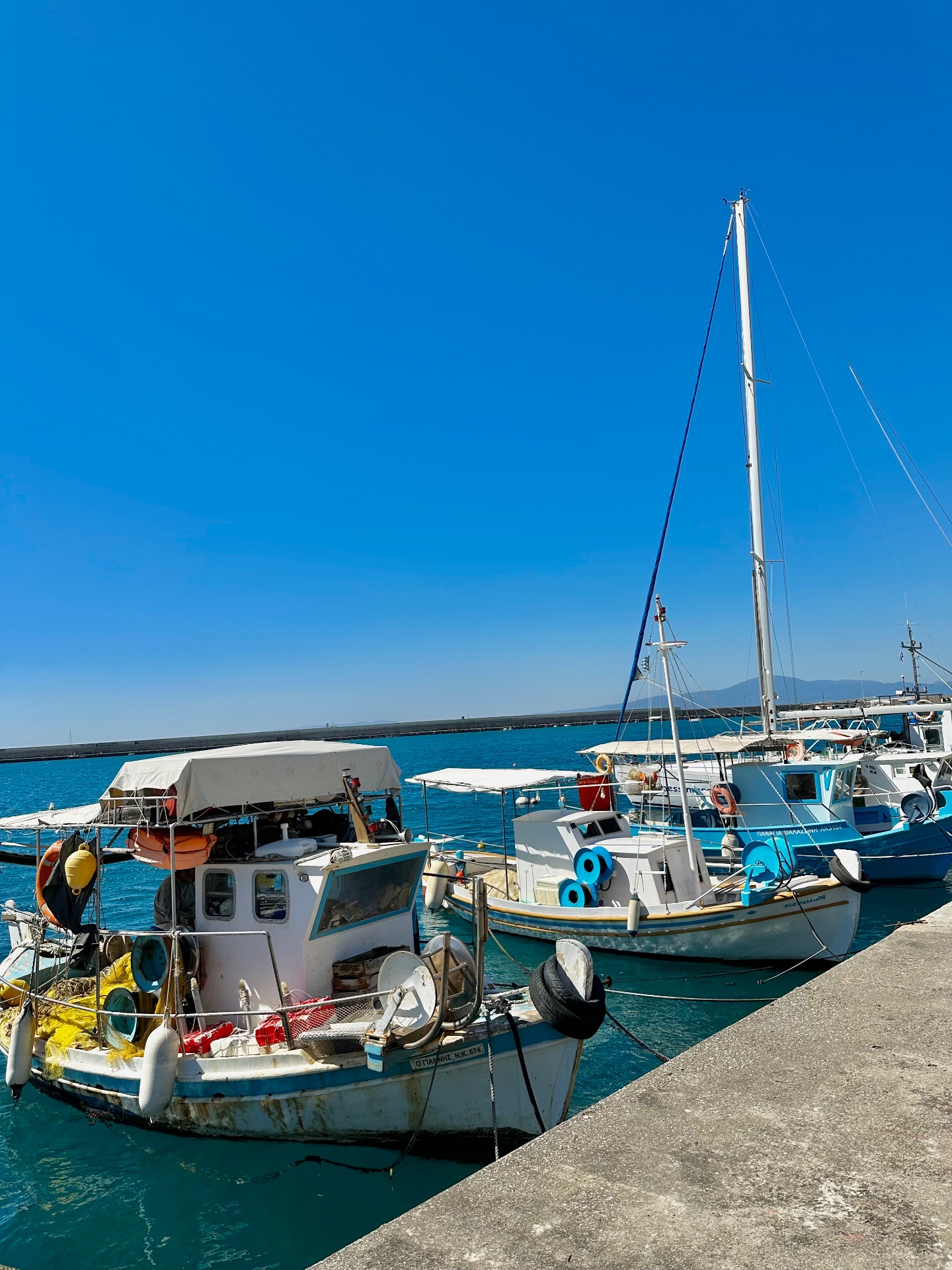 Fishing boats moored in a sunlit Greek harbor